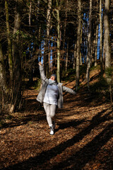 Fototapeta premium Caucasian female adult joyfully walking in autumn forest