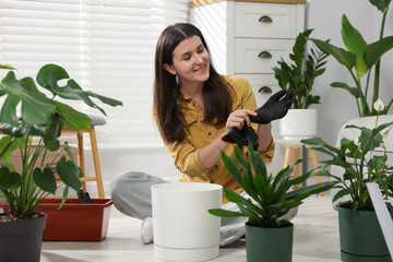 Transplanting. Woman with different potted houseplants on floor at home