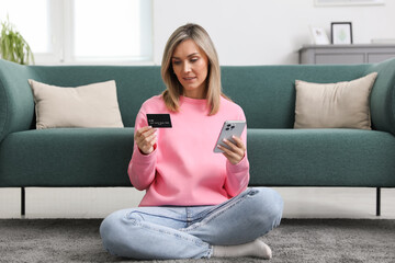 Obraz premium Woman making online payment with phone and credit card indoors