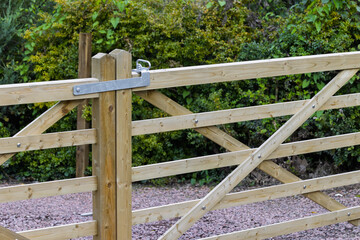 Fototapeta premium Closed wooden driveway gate with a metal latch and timber posts