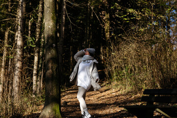 Fototapeta premium Young caucasian female enjoying sunshine on woodland trail in autumn