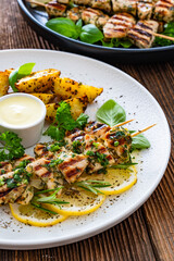 Greek style chicken skewers souvlaki with baked potatoes on wooden background

