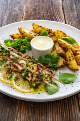 Greek style chicken skewers souvlaki with baked potatoes on wooden background

