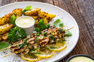Greek style chicken skewers souvlaki with baked potatoes on wooden background

