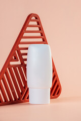 White cosmetic product or sunscreen cosmetic with stylish props on light orange background.