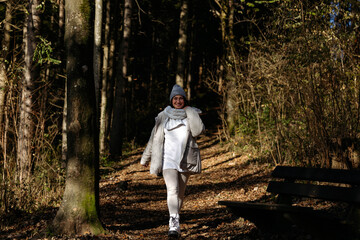 Fototapeta premium Smiling caucasian female walking in forest during autumn
