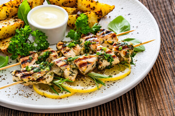 Greek style chicken skewers souvlaki with baked potatoes on wooden background

