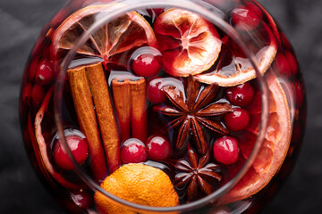 Close up of red mulled wine glass with slices of orange, cinnamon stick, star anise and cranberries. Christmas and winter holidays concept. Food photography
