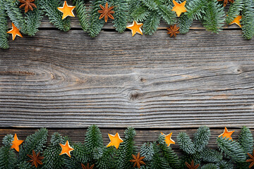 Christmas or New Year background with a border of green fir branches, dried lime and orange slices, anis stars and pine cones. Rustic wooden Ornament Border Background