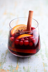 Christmas drink - red spiced mulled wine in glass with slices of orange, cinnamon, star anise and cranberries