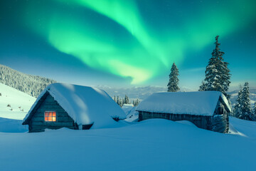 Fototapeta premium Aurora Borealis over snowy mountain landscape with a small cozy house. Colorful Northern lights in winter night nature