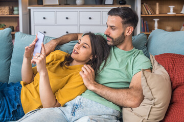 Couple relaxes together, taking a selfie on a smartphone, laughing at messages, sharing photos, scrolling the feed, planning weekend, replying to friends, and saving moments to the gallery today