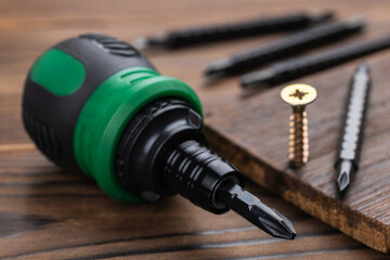 screwdriver and screws on wooden background close up
