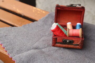 Vintage Red Sewing Box With Spools Of Thread On Grey Fabric And Craft Supplies