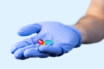 medical worker or pharmacist hands wearing blue latex protective gloves, hold red and green...