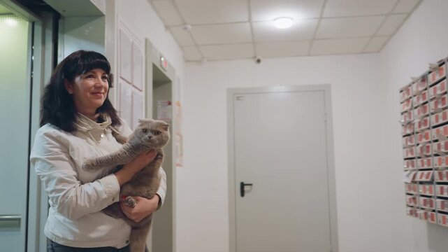 Lady Gently Holds Feline Nearby, Resident Woman Peacefully Grasps Her Cat Near Apartment Postal Area, Woman In City Calmly Holds Her Feline Companion Near Mail Station Outside Her Residence