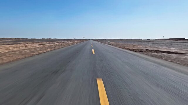 Drive car fast on a straight asphalt road in the desert under blue sky