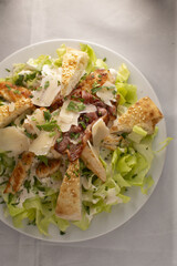 Grilled chicken caesar with romaine, parmesan, croutons, creamy dressing on bright plate, highcontrast light, satisfying protein lunch for active lifestyle