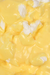 A close-up, vertical full-frame background of white meringue 'floating islands' covered in creamy yellow custard, known as snenokle or ile flottante