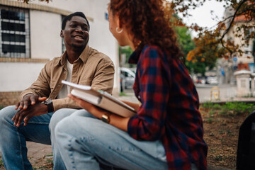 Two college students talking and studying outdoors on campus