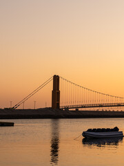 serene waterfront sunset with boats drifting under warm golden light