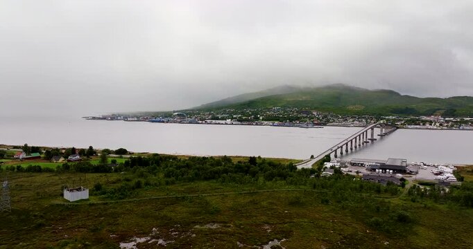 Aerial view of Sortland in Northern Norway, showcasing the long bridge, calm coastal waters, and surrounding Vester&aring;len landscape under soft misty weather conditions