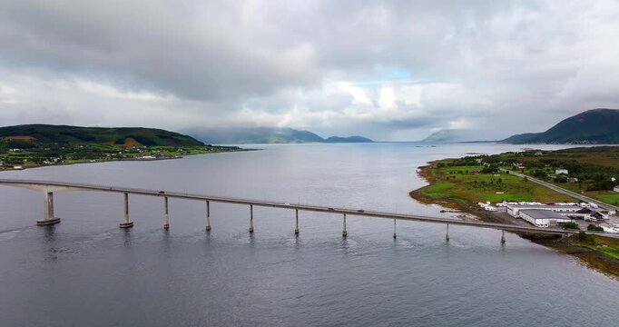 Aerial drone view of cars driving across the Sortland Bridge in Vester&aring;len, Norway. The concrete structure spans the fjord connecting the islands under a moody cloudy sky