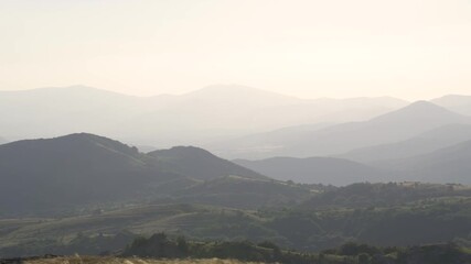 Pan shot of distant mountains in the late afternoon. Light fog covers the landscape. Perspective. Stara planina in the region of Sliven town. Balkan Mountains.