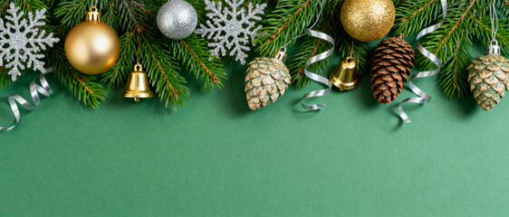 Festive evergreen christmas border with glitter baubles pine cones silver snowflakes and curled ribbons on green background for winter decor