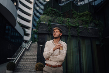 Businessman drinking coffee outside modern office building