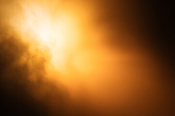 Bright light shines through clouds at night creating an orange glow in the sky