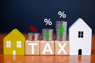 Real estate tax concept with stacked coins showing changing interest rates, wooden house models, and financial growth indicators for property investment, mortgage planning, and economic analysis.