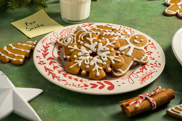 Holiday background. Christmas gingerbread cookies for Santa in a plate with glass of milk, festive food, home baking. Flat lay