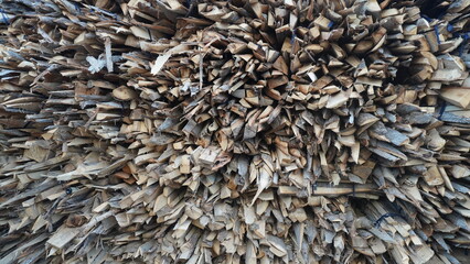 Close-up of stacked firewood logs with rough, jagged edges creating a dense, textured pattern, chopped concept.