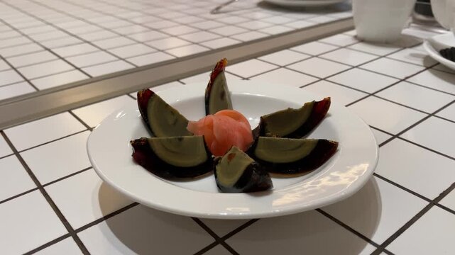 4k video footage of Century egg cut into six pieces and served on a white plate on a dining table.