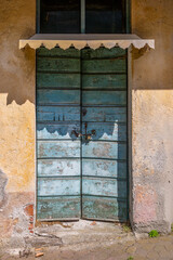 Rustic charm and history captured in this old wooden door painted in blue and green, with paint chipped away by time and an authentic rusty padlock.