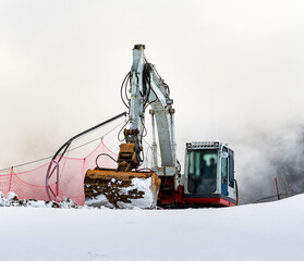 close-up of an excavator working in the snowy mountains