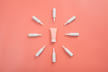 Pink cream tube surrounded by white applicators on a peach surface