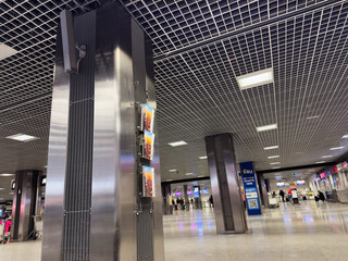 Naklejka premium Modern Krakow airport terminal in Poland with metallic columns posters and travelers in the distance