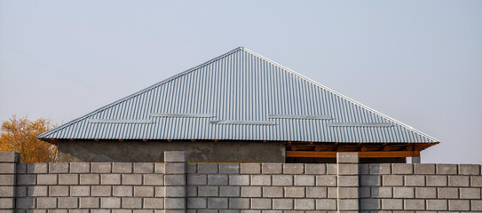 Gray roof with a triangle shape and a wall made of bricks