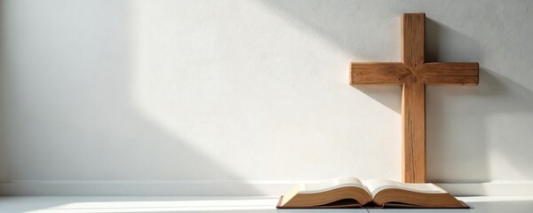 Wooden cross stands near opened bible. Minimalist design on white background with soft shadows. Spiritual composition provides copy space. Suitable for church events, sermon series announcements