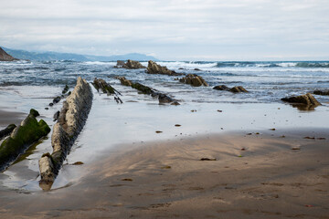 Coastal Beach With Rocky Outcrops and Cliffside Shoreline Under Cloudy Sky