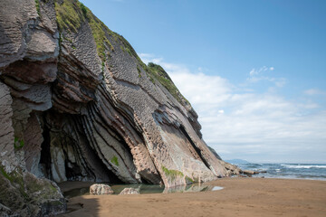 Majestic Coastal Cliff With Layered Rock Forms Over a Sandy Beach by the Sea
