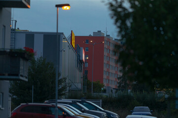 A long row of parked cars can be seen in front of a tall building during the night, illuminated by street lights and city lights