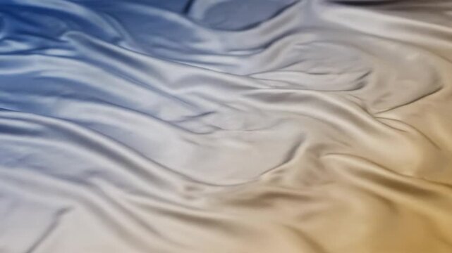 Luxurious satin fabric rippling gently with blue and gold gradient colors creating smooth and flowing waves