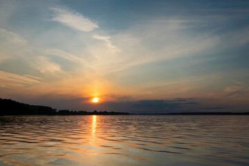 Sunset and its reflection in the water and waves of the reservoir