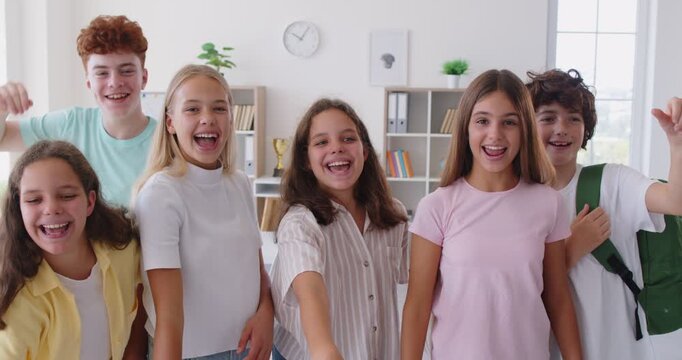 Schoolchildren launch colorful paper airplanes, demonstrating their creativity and teamwork. Cheerful preteen girls and boys in school classroom throw paper airplanes at camera. 4k video.