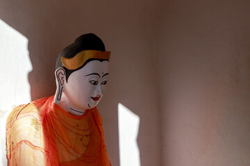 Peaceful Buddha statue with calm expression in spiritual temple setting. Sunlight and shadow create serene atmosphere, quiet place for meditation, belief, and tranquility