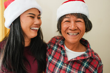 Happy asian mother and daughter having fun together during Christmas time wearing Santa Claus hat - Holiday and family concept - Main focus on mother nose
