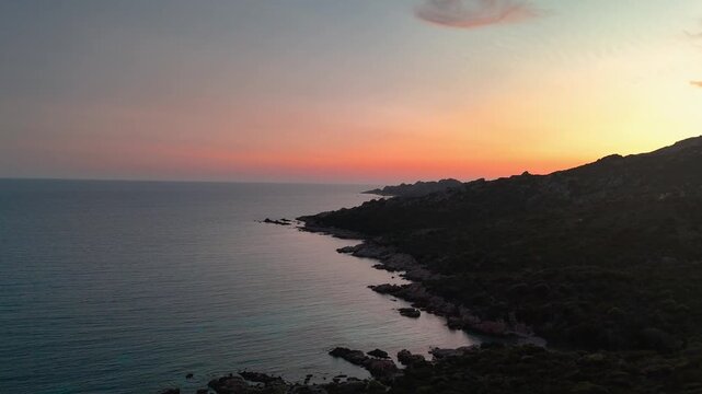 Smooth Aerial Drone Gliding Over Rugged Capu di Fenu Landscape Towards the Horizon and Dramatic Setting Sun Over the Mediterranean Sea, Corsica, France.